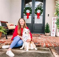 meagan sitting with her dog on the front porch with christmas wreaths on the door in the background
