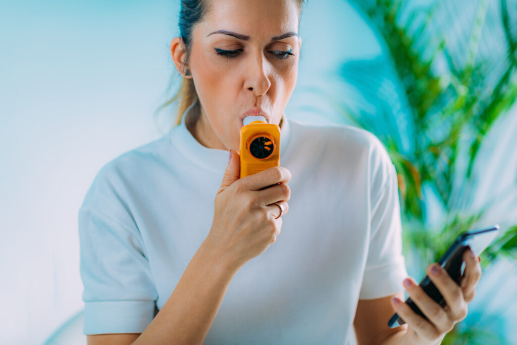 woman using portable spirometer and iphone app